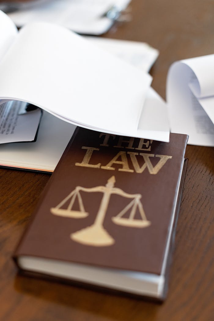 A Law Book on a Wooden Desk Beside Papers
